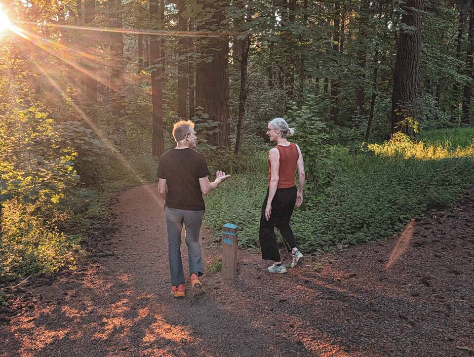 Brian and a member talking on a golden Mt. Tabor trail, sun coming through the firs